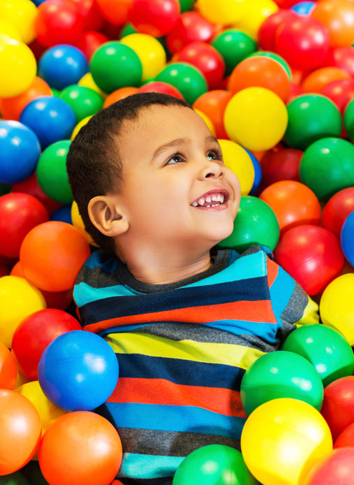 photo of boy swimming in a playground full of colorful balls
