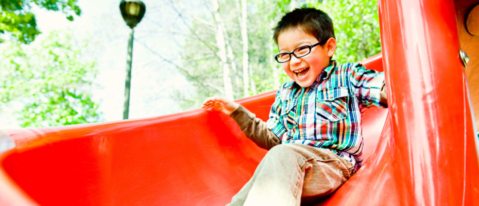 Photo of boy sliding down a slide at a park